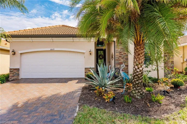 View of front of property featuring lush landscaping and a Sylvester palm