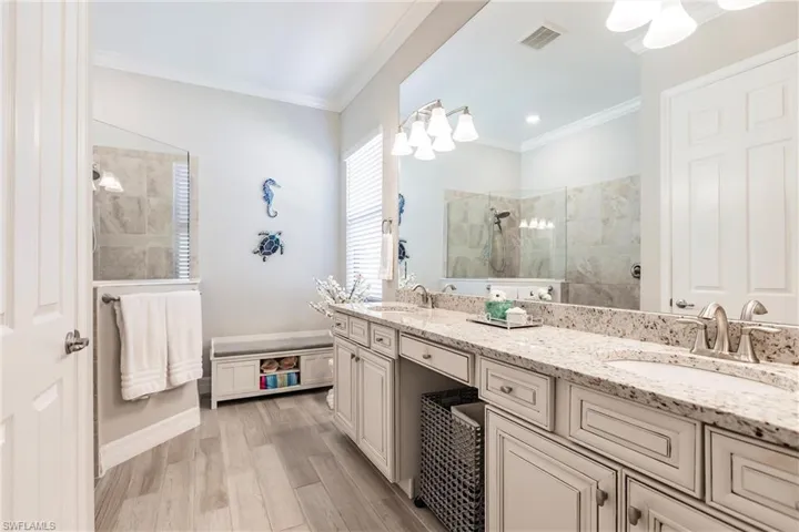 Bathroom with double sink vanity, tile  floors, a tile shower, and crown molding