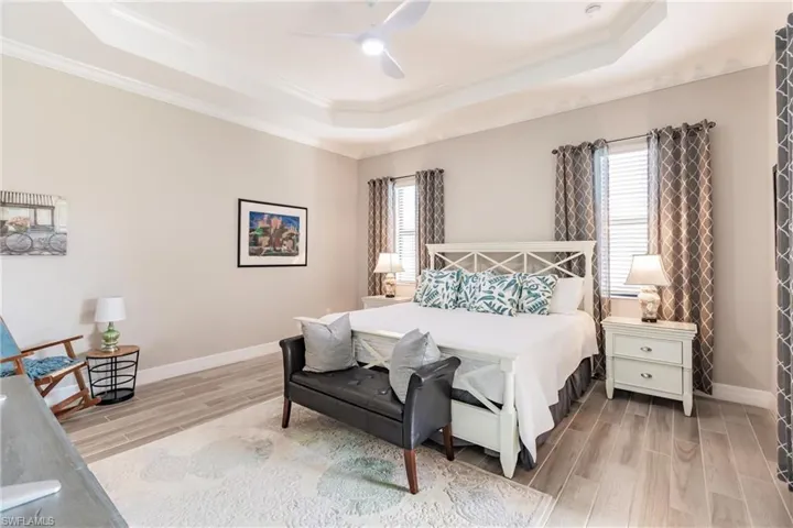 Bedroom with multiple windows, a tray ceiling, and light plank tile flooring