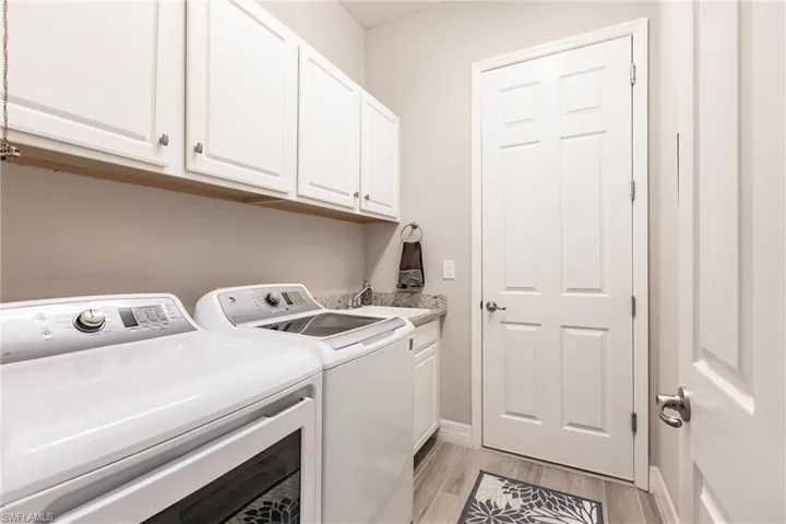 Laundry area featuring sink, tile floors, cabinets, and washer and clothes dryer