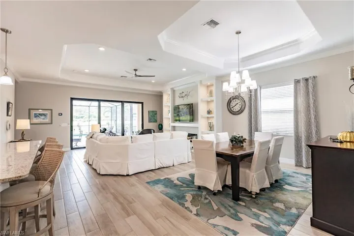 Dining area with a tray ceiling, a wealth of natural light, and ceiling fan with notable chandelier