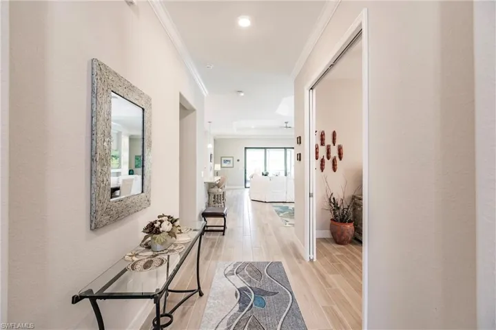 Corridor featuring crown molding and light plank tile flooring