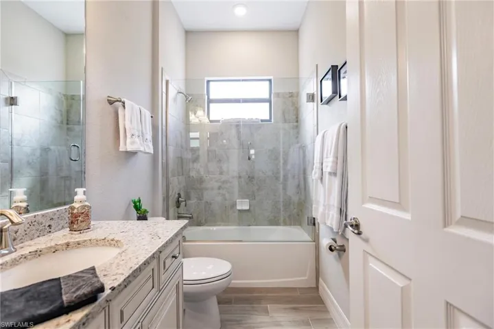 Guest full bathroom featuring vanity, toilet, and shower / bath combination with seamless glass door