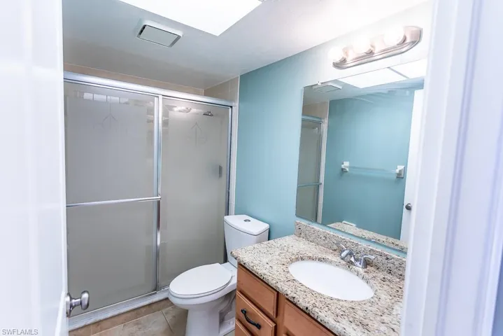 Bathroom with tile patterned floors, an enclosed shower, vanity, and toilet