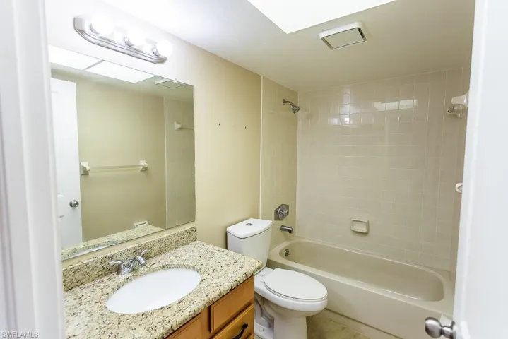 Full bathroom with tiled shower / bath combo, tile patterned floors, toilet, and vanity