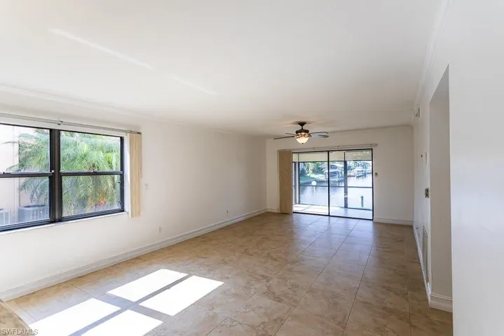 Tiled empty room with ceiling fan and ornamental molding