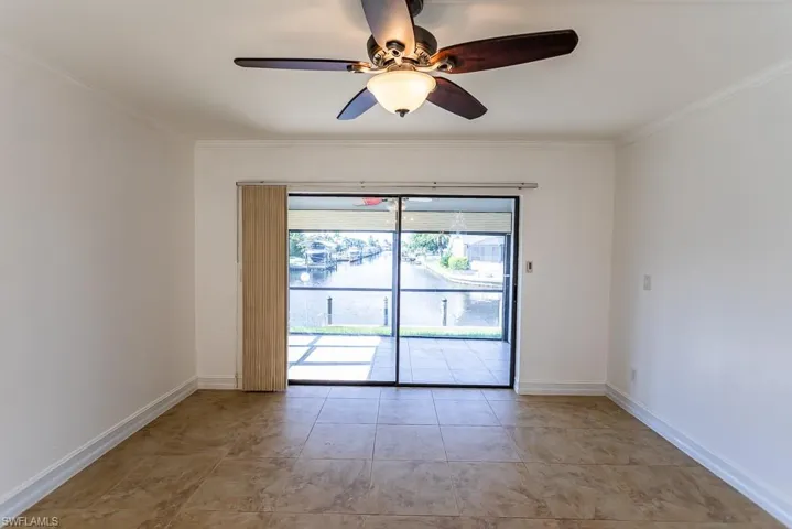 Empty room featuring ceiling fan, light tile patterned floors, and crown molding