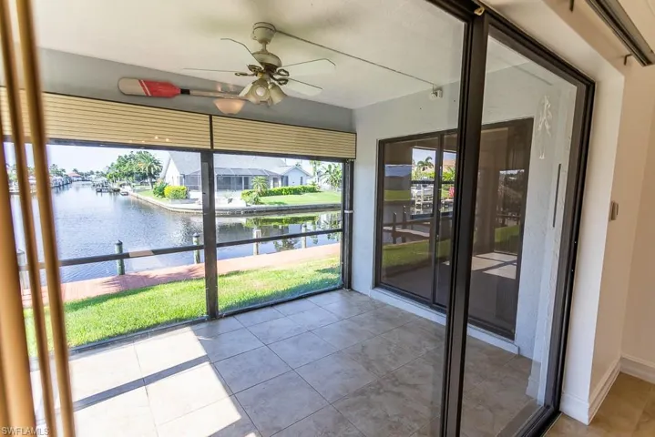 Unfurnished sunroom featuring ceiling fan and a water view