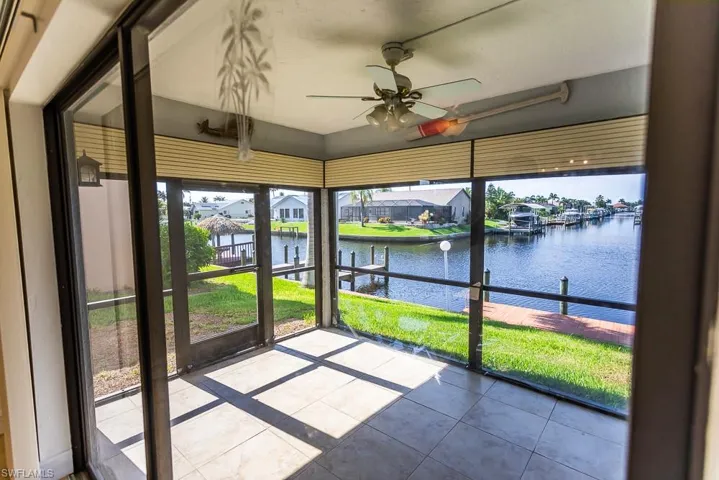 Unfurnished sunroom featuring ceiling fan and a water view