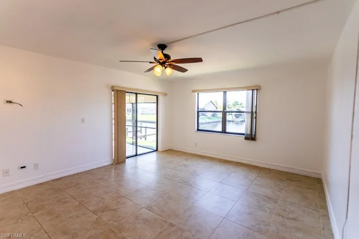 Empty room with ceiling fan and light tile patterned floors