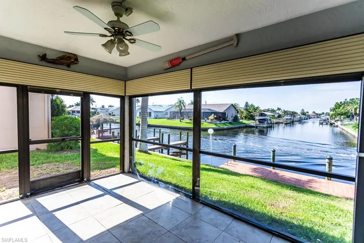 Unfurnished sunroom with ceiling fan, a wealth of natural light, and a water view