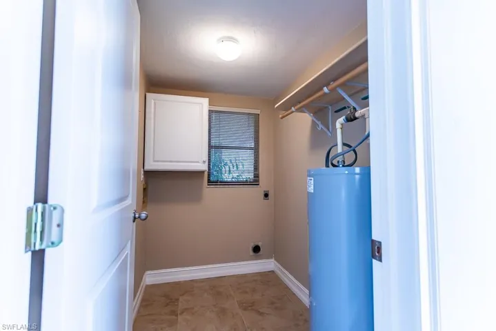 Washroom featuring hookup for an electric dryer, gas water heater, and light tile patterned flooring