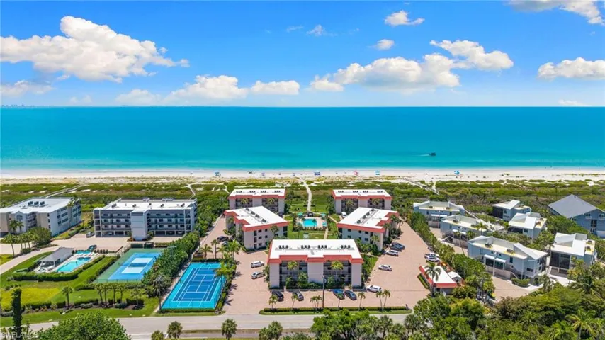 Coastal community featuring multiple residential buildings, direct beach access, a swimming pool, and two tennis courts