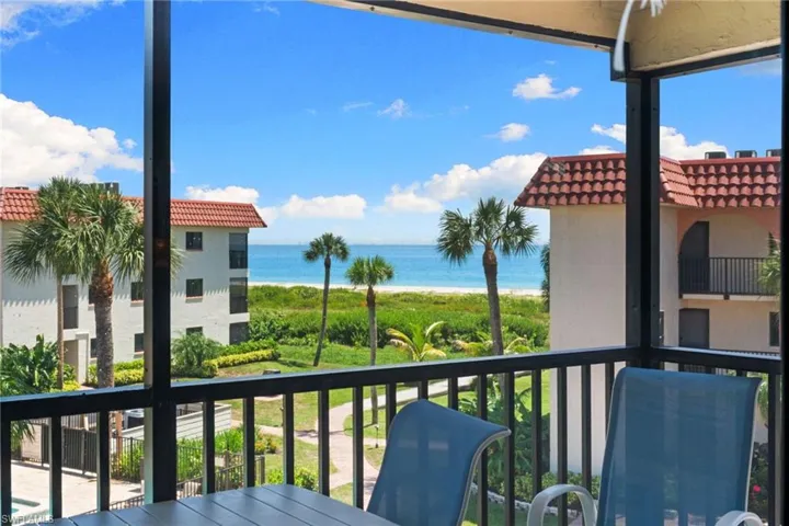 Screened balcony with direct ocean frontage, surrounded by tropical landscaping and mature palm trees