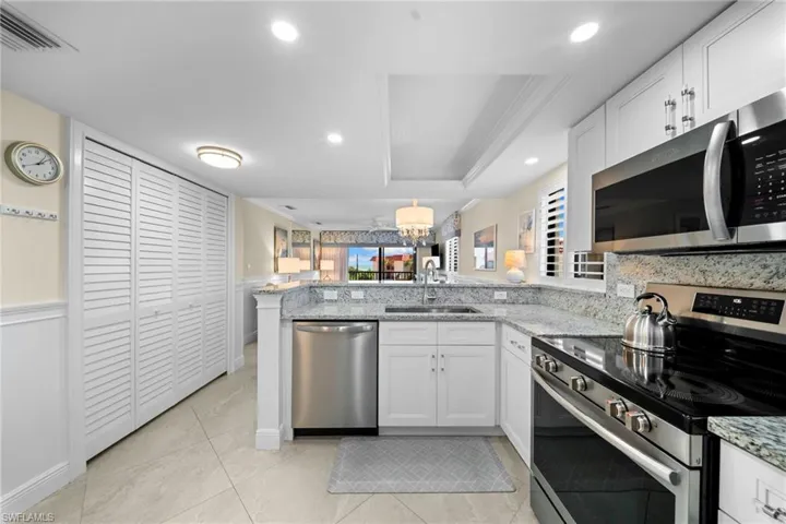 Kitchen featuring stainless steel appliances, white cabinetry, and light-toned countertops