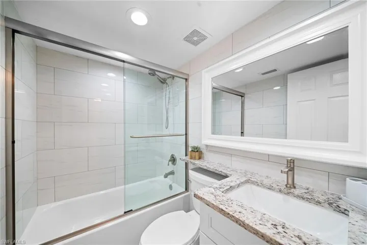 White subway-style tiled shower surround with glass enclosure and sliding door