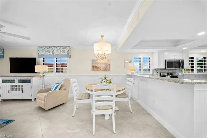 Open concept living area with light-toned tile flooring, tray ceiling, and crown molding