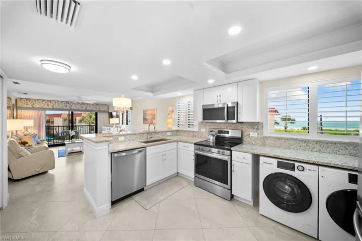 Open-concept kitchen with stainless steel appliances, white cabinetry, and light-toned countertops