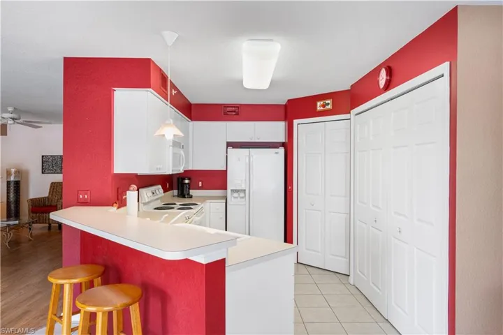 Kitchen with ceiling fan, hanging light fixtures, white appliances, light hardwood / wood-style flooring, and kitchen peninsula