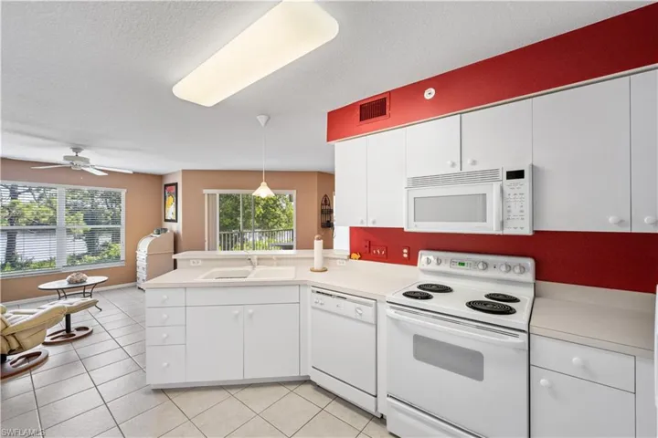 Kitchen featuring white appliances, sink, hanging light fixtures, white cabinetry, and ceiling fan
