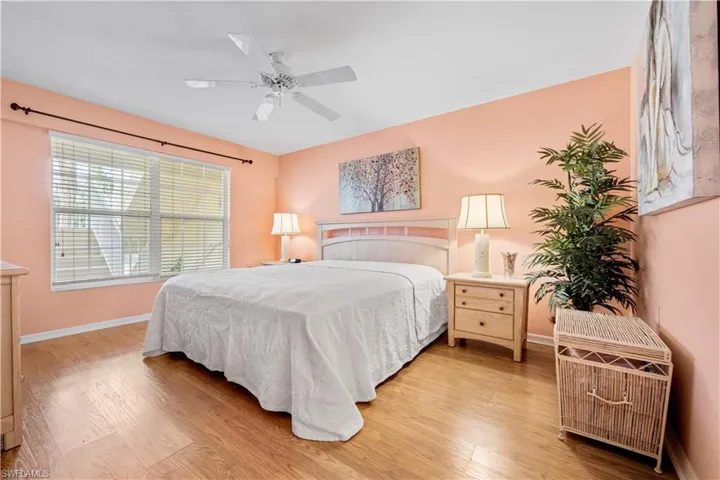 Bedroom with light hardwood / wood-style flooring and ceiling fan. Lots of natural light spills in almost every room in this condo!