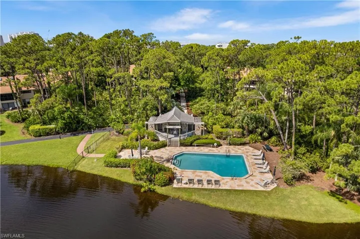 View of community pool with a water view, a patio, and a lawn