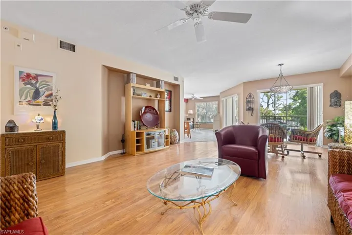 Living room with a textured ceiling, ceiling fan, and light wood-type flooring