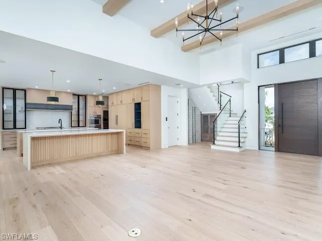 Kitchen featuring open floor plan, light wood finish cabinetry, light wood finished floors, hanging lights, and light stone counters