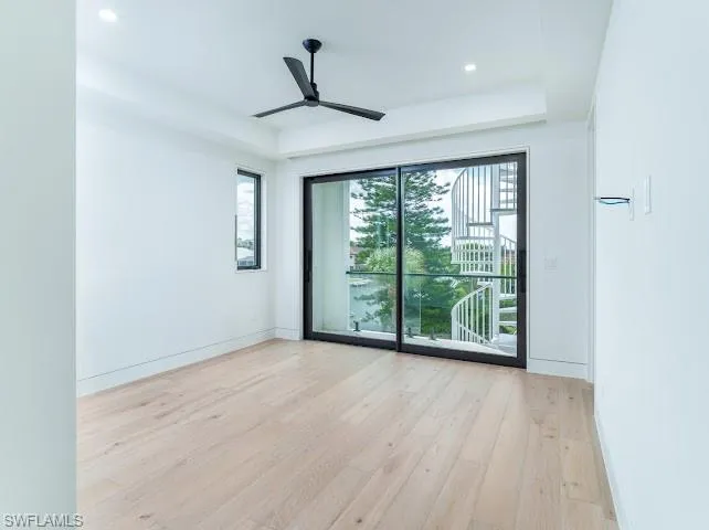 Empty room with light wood-type flooring, a ceiling fan, a raised ceiling, and recessed lighting