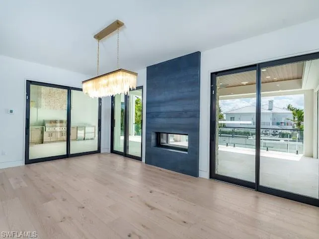 Unfurnished dining area featuring light wood-type flooring, hanging lights, and a multi sided fireplace