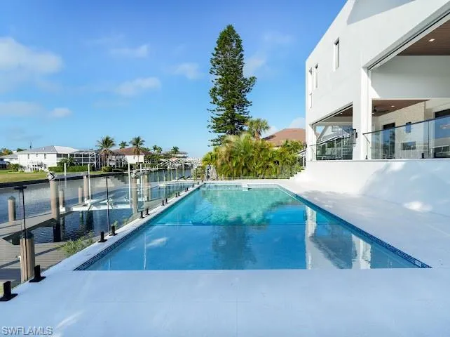 Outdoor pool with a patio area, a boat dock, boat lift, and a residential view