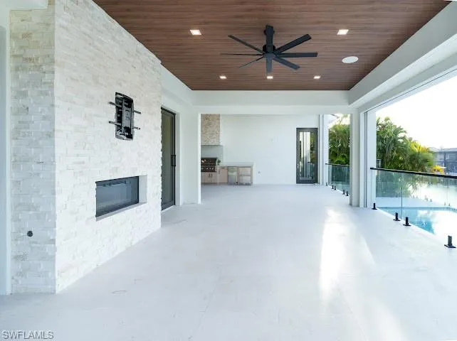 View of patio / terrace featuring exterior kitchen, ceiling fan, and an outdoor pool