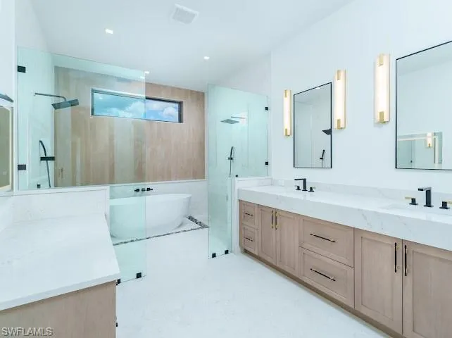 Full bath with a walk in shower, double vanity, and a freestanding bath