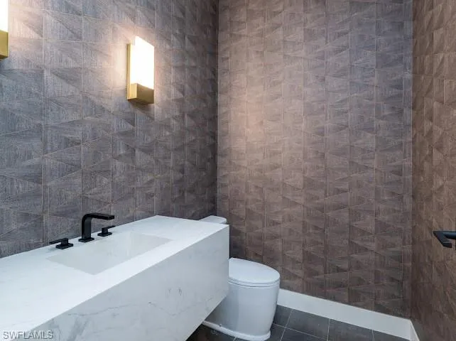 Bathroom with tile walls, vanity, and dark tile patterned flooring