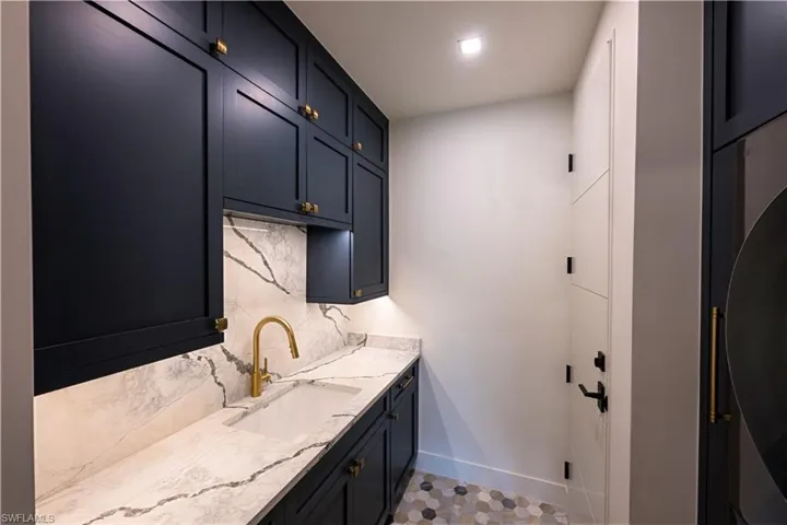 Laundry room with a sink and baseboards