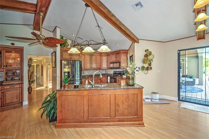 Kitchen featuring ceiling fan, black appliances, light hardwood / wood-style flooring, and kitchen peninsula