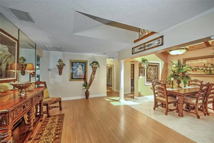 Dining space with light hardwood / wood-style floors, crown molding, decorative columns, and a textured ceiling