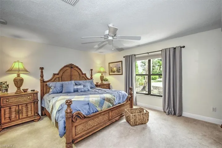 Bedroom featuring light carpet, a textured ceiling, and ceiling fan