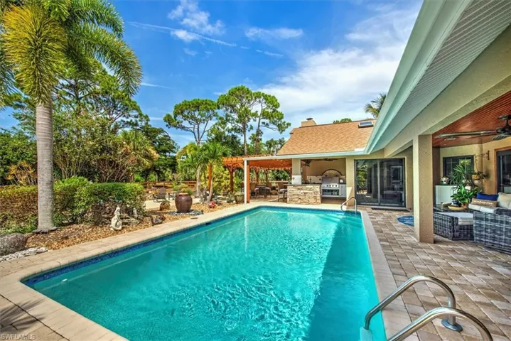 View of swimming pool with exterior kitchen, ceiling fan, a patio, an outdoor hangout area, and grilling area