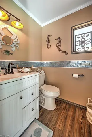 Bathroom with vanity, ornamental molding, toilet, and hardwood / wood-style floors