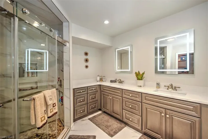 Bathroom with dual vanity, an enclosed shower, and tile patterned floors