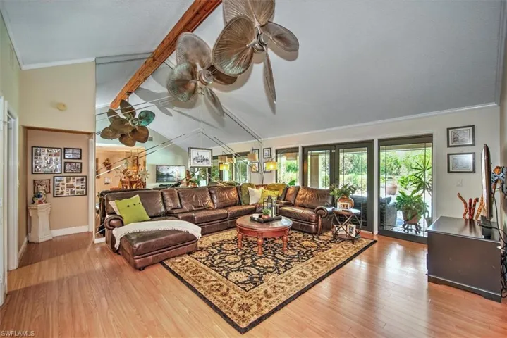 Living room with lofted ceiling with beams, crown molding, and light hardwood / wood-style flooring