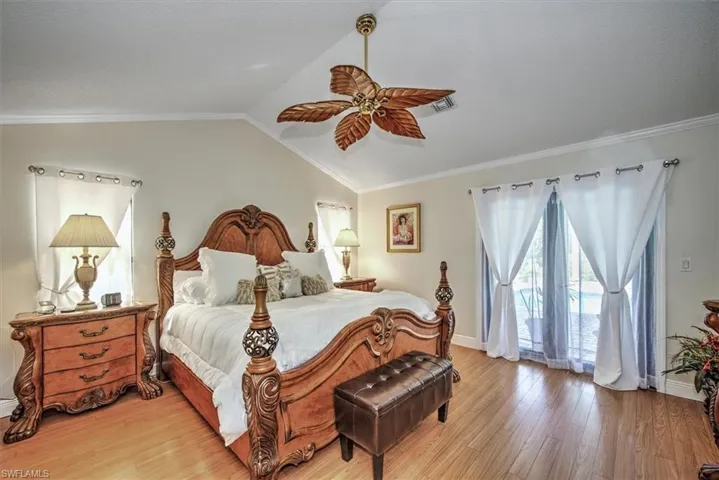 Bedroom featuring light hardwood / wood-style floors, crown molding, vaulted ceiling, and ceiling fan