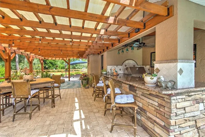 View of patio featuring ceiling fan, a bar, and a pergola