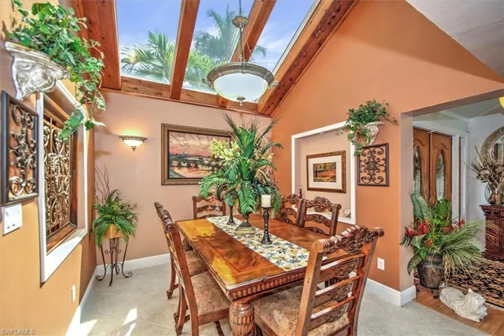 Tiled dining room featuring beamed ceiling and high vaulted ceiling