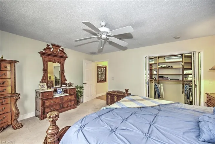 Bedroom with a textured ceiling, light colored carpet, a closet, and ceiling fan