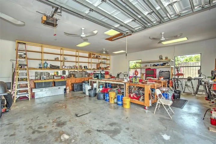 Garage with a workshop area, a garage door opener, and ceiling fan