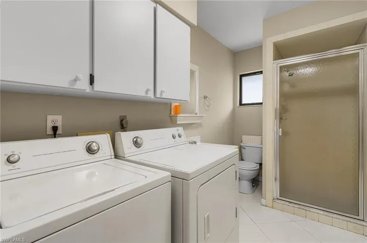 Clothes washing area featuring washer and clothes dryer and light tile patterned floors