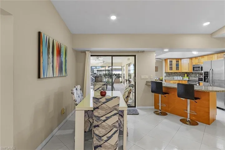 Kitchen with decorative backsplash, kitchen peninsula, light stone counters, a breakfast bar, and stainless steel appliances