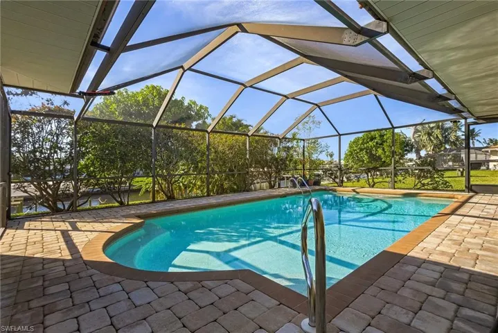 View of swimming pool with glass enclosure and a patio